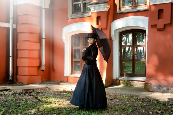 19世纪 身穿严格的黑色衣服的神秘而美丽的女士 带着怀疑的目光凝视着黑暗的古堡 19世纪 20世纪初的风格 — 图库照片