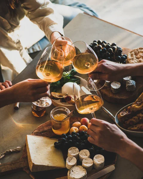 お菓子の上にオレンジやバラのワインとグラスをクリックしている人の手は 具体的な背景にチーズブドウパン ワインの試飲会のコンセプト — ストック写真