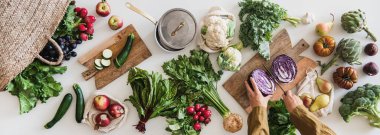 Sonbahar vejetaryen yemek geçmişi. Kadın eli, taze mevsimlik sebzeler, sebzeler, sebzeler ve marketten alınmış meyvelerle kırmızı lahana pişiriyor. Vegan, sağlıklı, organik yiyecekler.