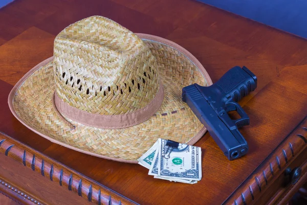 Hat, handgun and money on wooden desk — Stock Photo, Image