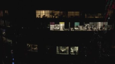 Geceleri ofisleri olan modern gökdelenin cam cephesindeki drone 'dan hava görüntüsü