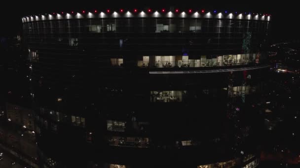 Geceleri ofisleri olan modern gökdelenin cam cephesindeki drone 'dan hava görüntüsü — Stok video
