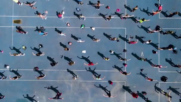 Вид с беспилотника на группу людей, занимающихся гимнастикой, аэробикой и спортом — стоковое видео