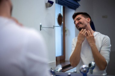 Nadir sakallı adam banyo aynasına dokunmuş gibi bakıyor.