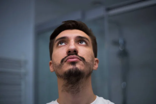 Portrait of a man with a bad heterogeneous beard in the bathroom