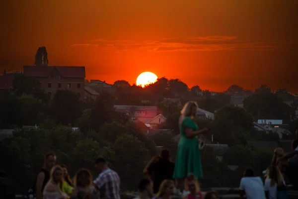 Pár mladých lidí sedí na okraji útesu jako západ slunce. — Stock fotografie