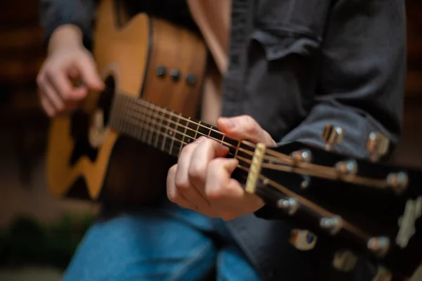 A guy clamps a chord on an acoustic guitar with close-up — Fotografia de Stock