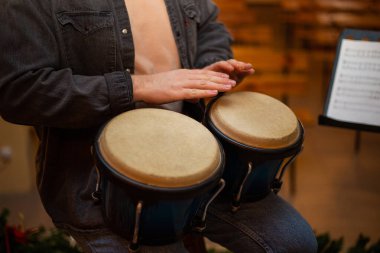 A young guy with a beard plays percussion bongos