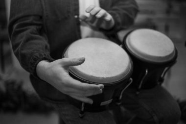 A young guy with a beard plays percussion bongos