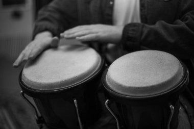 A young guy with a beard plays percussion bongos