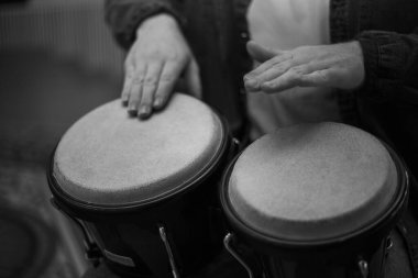 A young guy with a beard plays percussion bongos