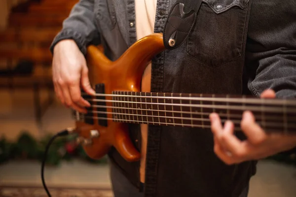 A young guy with a beard plays a bass guitar with five strings — Stockfoto