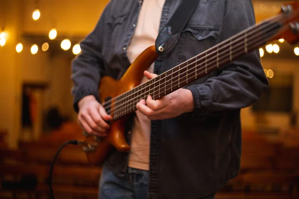 A young guy with a beard plays a bass guitar with five strings — Stok fotoğraf