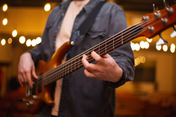 A young guy with a beard plays a bass guitar with five strings — Stok fotoğraf