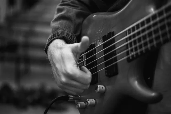 A young guy with a beard plays a bass guitar with five strings — Stockfoto