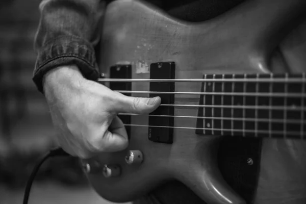 A young guy with a beard plays a bass guitar with five strings — Stockfoto