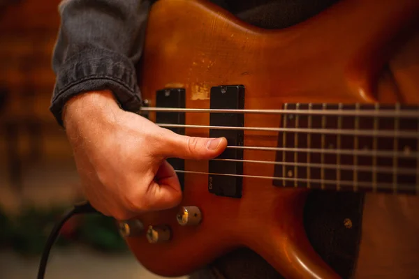 A young guy with a beard plays a bass guitar with five strings — Stockfoto