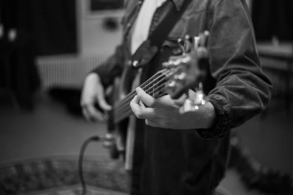 A young guy with a beard plays a bass guitar with five strings — Stock Fotó