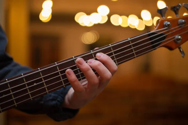 A young guy with a beard plays a bass guitar with five strings — Stockfoto