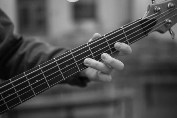 A young guy with a beard plays a bass guitar with five strings — Foto Stock
