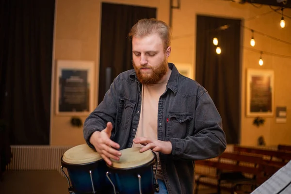 A young guy with a beard plays percussion bongos — Foto de Stock