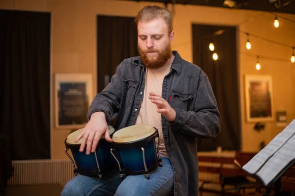 Un joven con barba toca bongos de percusión — Foto de Stock