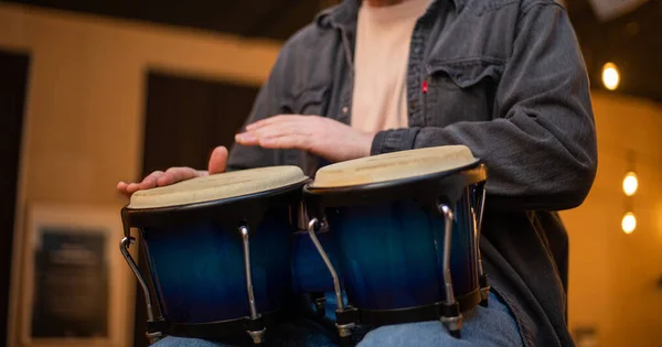 Un joven con barba toca bongos de percusión — Foto de Stock