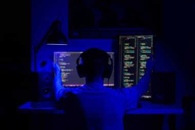 Hayal kırıklığına uğramış bir adam, geceleri bir masada bilgisayar başında mavi ışık ve programlarla oturuyor.