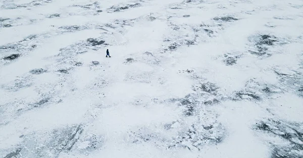Luftaufnahme von oben: Eine Person wandert im Winter zwischen einem vereisten See — Stockfoto