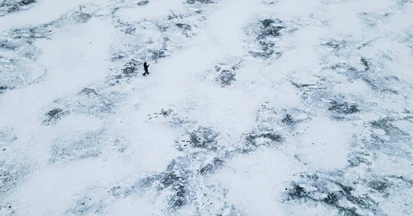 Luftaufnahme von oben: Eine Person wandert im Winter zwischen einem vereisten See — Stockfoto
