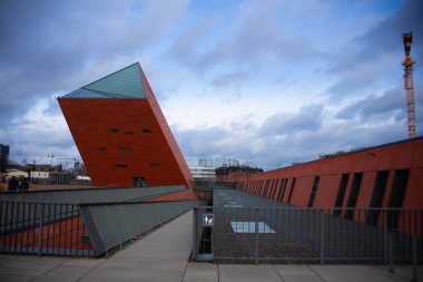 Modern mimari, düz ve eğimli çizgiler, cephenin kırmızı rengi ve bir sürü cila.