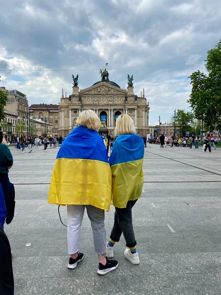 Lviv, Ukrayna 14.05.2022 - Ukrayna bayrağıyla kaplanmış iki Ukraynalı vatansever kadın birbirlerine yakın dururlar