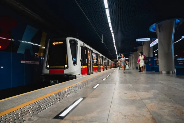 Varşova 'daki Dworzec Wilenski metro istasyonu M2 hattında yaklaşan bir trenle Ksiecia Janusza istikametinde birçok insan platformda yürüyor.