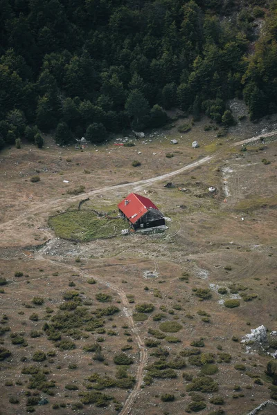 Arnavutluk 'un lanetli dağlarındaki bir ormanın ortasında harap olmuş kırmızı çatılı terk edilmiş eski bir ahşap ev yukarıdan görüldüğü üzere
