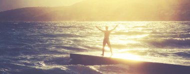 Özgürlük duygusu konsepti. Adam büyük dalgalarla denize bakan iskelede duruyor..