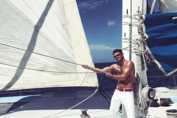 Yelkenli teknede tatilin tadını çıkaran bir adam..