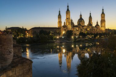 ZARAGOZA, SPAIN, 24 Ekim 2021, Bazilika del Pilar taş köprüden fotoğraf çeken turistlerle gün batımında Ebro Nehri 'nden geçerken yansıdı..