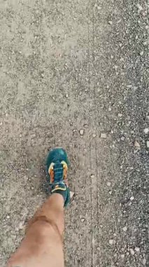 50 yaşında beyaz şortlu ve spor ayakkabılı bir adam forma girmek ve kilo vermek için taş bir yolda yürüyor..