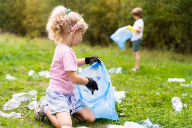 Çocuklar plastik çöpleri çıkarıp açık havada çözünebilir bir çöp torbasına koyuyorlar. Ekoloji, atık işleme ve doğa koruma kavramı. Çevre koruma.