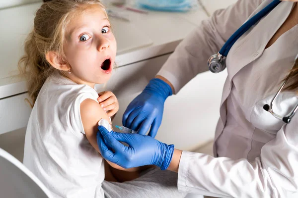 Çocukların aşılanması, doktor randevusundaki küçük bir kız, koluna iğne yapılması,.
