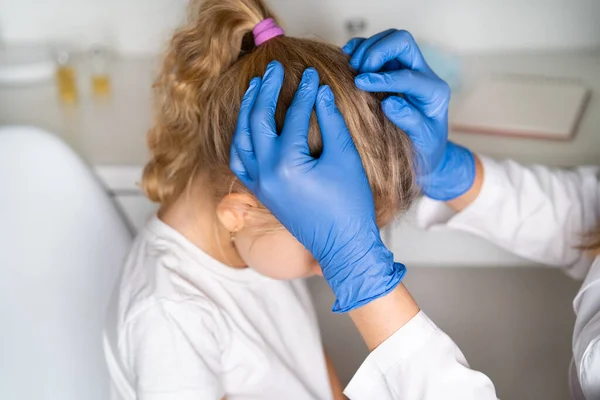 Bir dermatoloğun resepsiyonundaki küçük kız bit ve pediküloz için saç muayenesi yapıyor..
