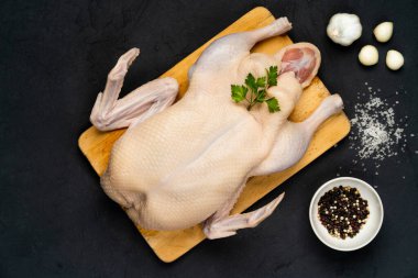 Taze çiğ ördek, ahşap bir tahtada, karanlık bir arka planda tuz ve biberle.