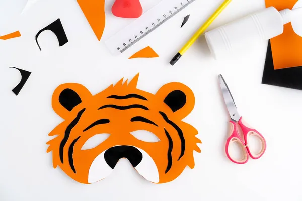 The process of making a childrens New Year tiger mask with a child made of colored paper, top view, symbol 2022, step-by-step — Stock Photo, Image