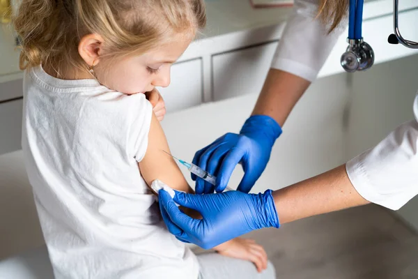 Вакцинация детей, маленькая девочка на приеме у врача, инъекция в руку, рожок — стоковое фото