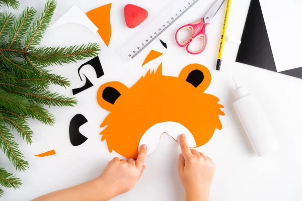 The process of making a childrens New Year tiger mask with a child made of colored paper, top view, symbol 2022, step 5 — Stock Photo, Image