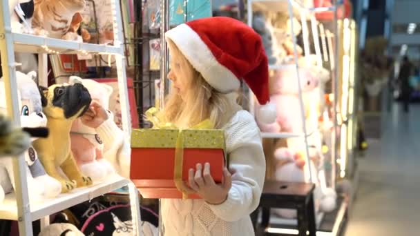 Niña en la tienda de juguetes recoge regalos de Navidad, Viernes Negro — Vídeos de Stock