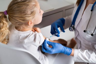 Çocukların aşılanması, doktor randevusundaki küçük bir kız, koluna iğne vurulması,
