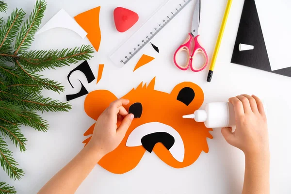 The process of making a childrens New Year tiger mask with a child made of colored paper, top view, symbol 2022, step-by-step — Stock Photo, Image