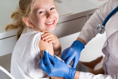 Çocukların aşılanması, doktor randevusundaki küçük bir kız, koluna iğne vurulması,