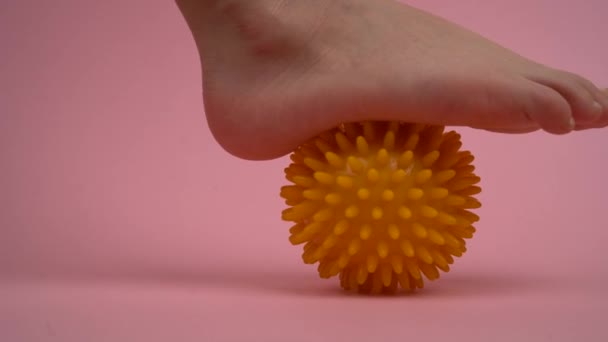 Профилактика плоскостопия и вальгуса стопы, упражнения с массажными шариками на розовом фоне — стоковое видео